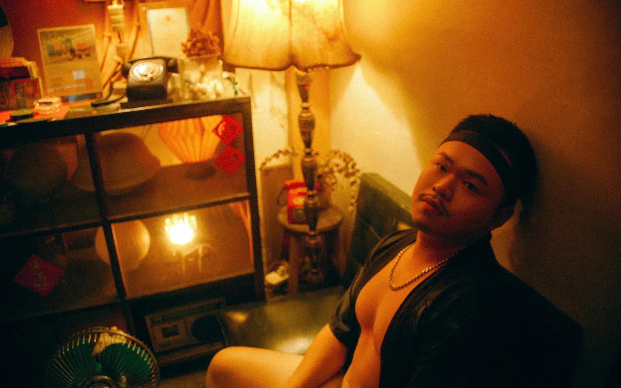 男子坐在昏黃燈光的房間角落，帶著沉思的神情 | 男性寫真攝影 | 宇宙拿鐵