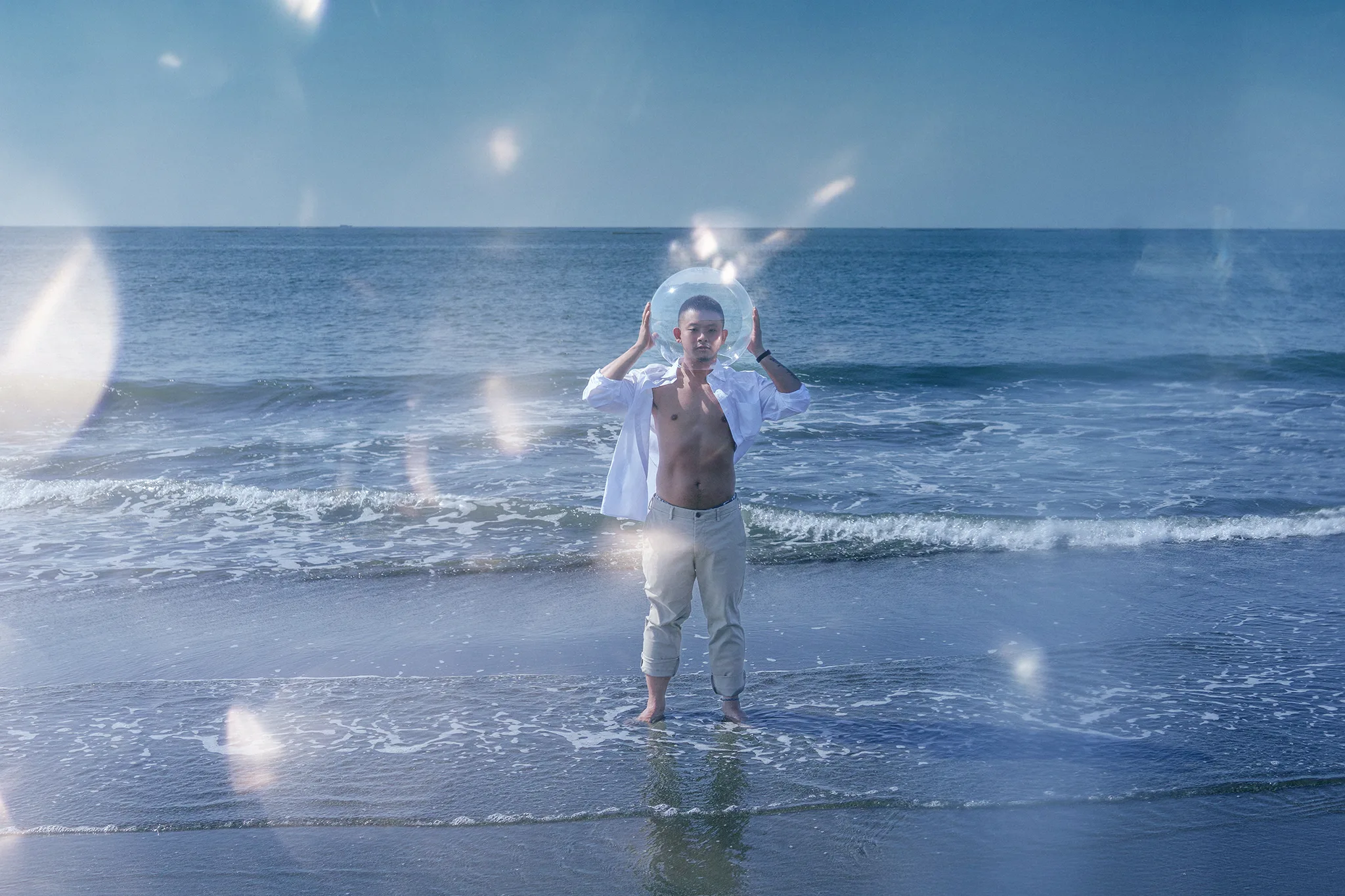 男性戶外寫真：海浪中舉起透明氣泡的動態瞬間